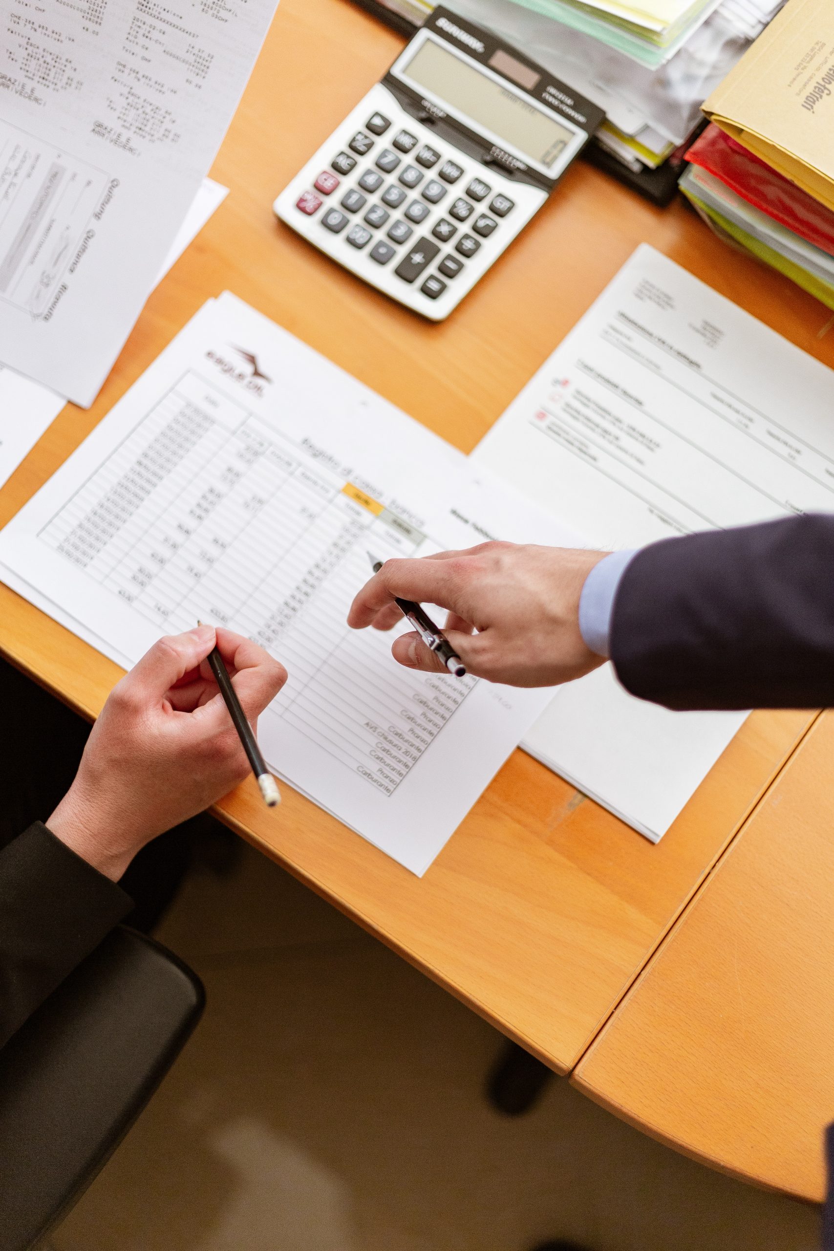 two-person-holding-pens-pointing-at-printer-paper-2058134